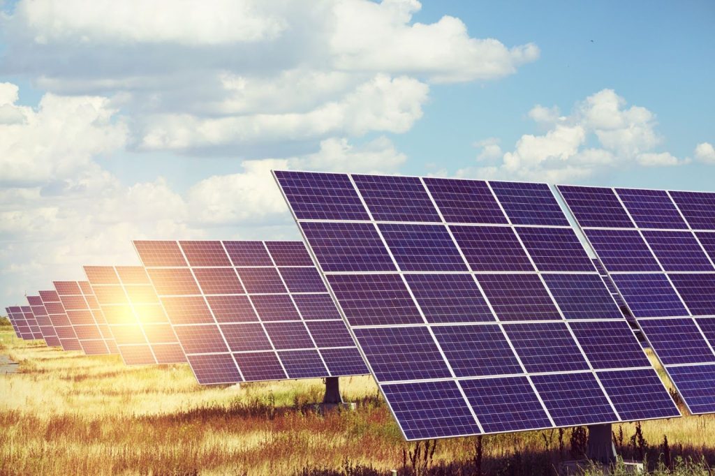 Photo Of Sunlight Behind Many Models Of Solar Panels On a Field